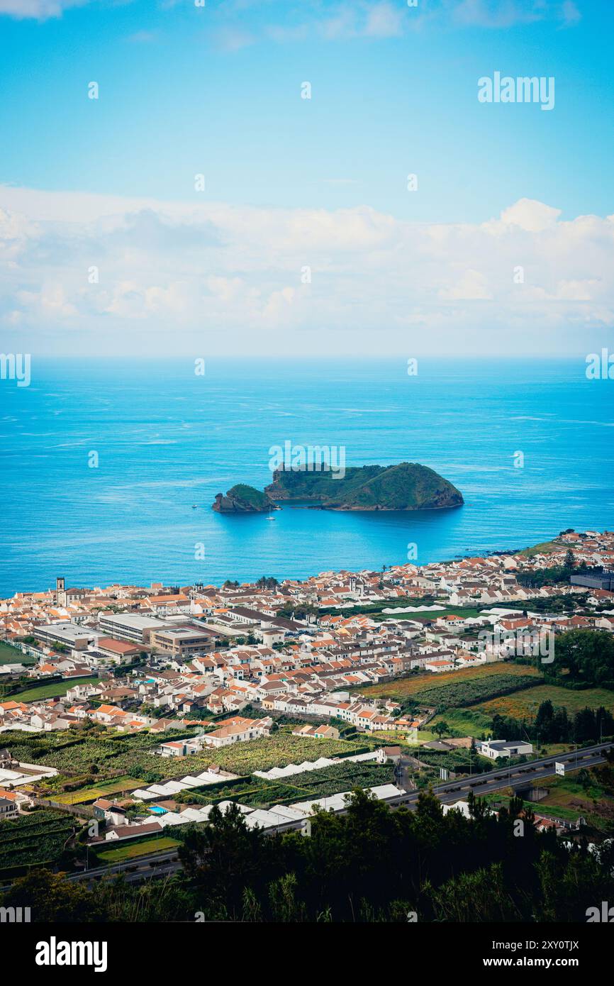 Cette superbe photographie capture une vue aérienne panoramique d'une ville animée des Açores, mettant en valeur la végétation luxuriante, la disposition structurée de la ville, et Banque D'Images