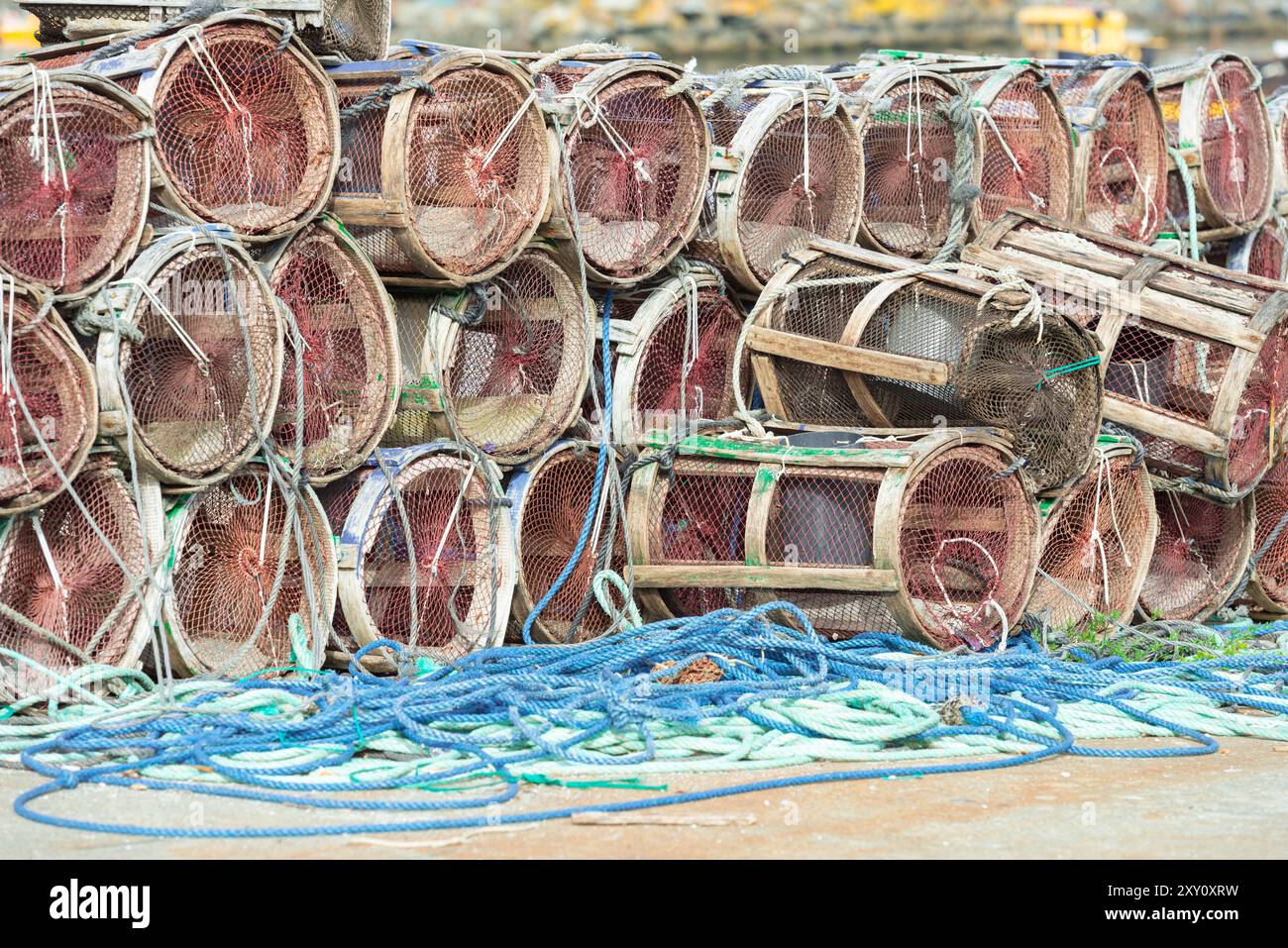 Une collection de divers pièges de pêche empilés accompagnés de cordes à un quai en bord de mer, mettant en valeur l'équipement utilisé dans les industries de la pêche commerciale Banque D'Images
