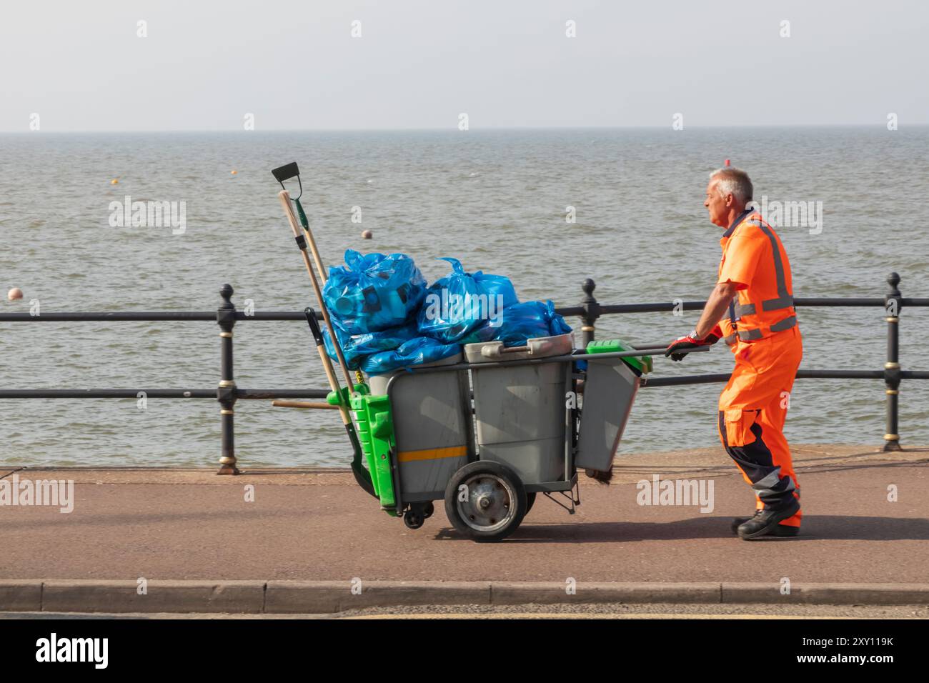 Angleterre, Kent, Herne Bay, Seafront Promenade Street Cleaner avec poubelles débordantes Banque D'Images