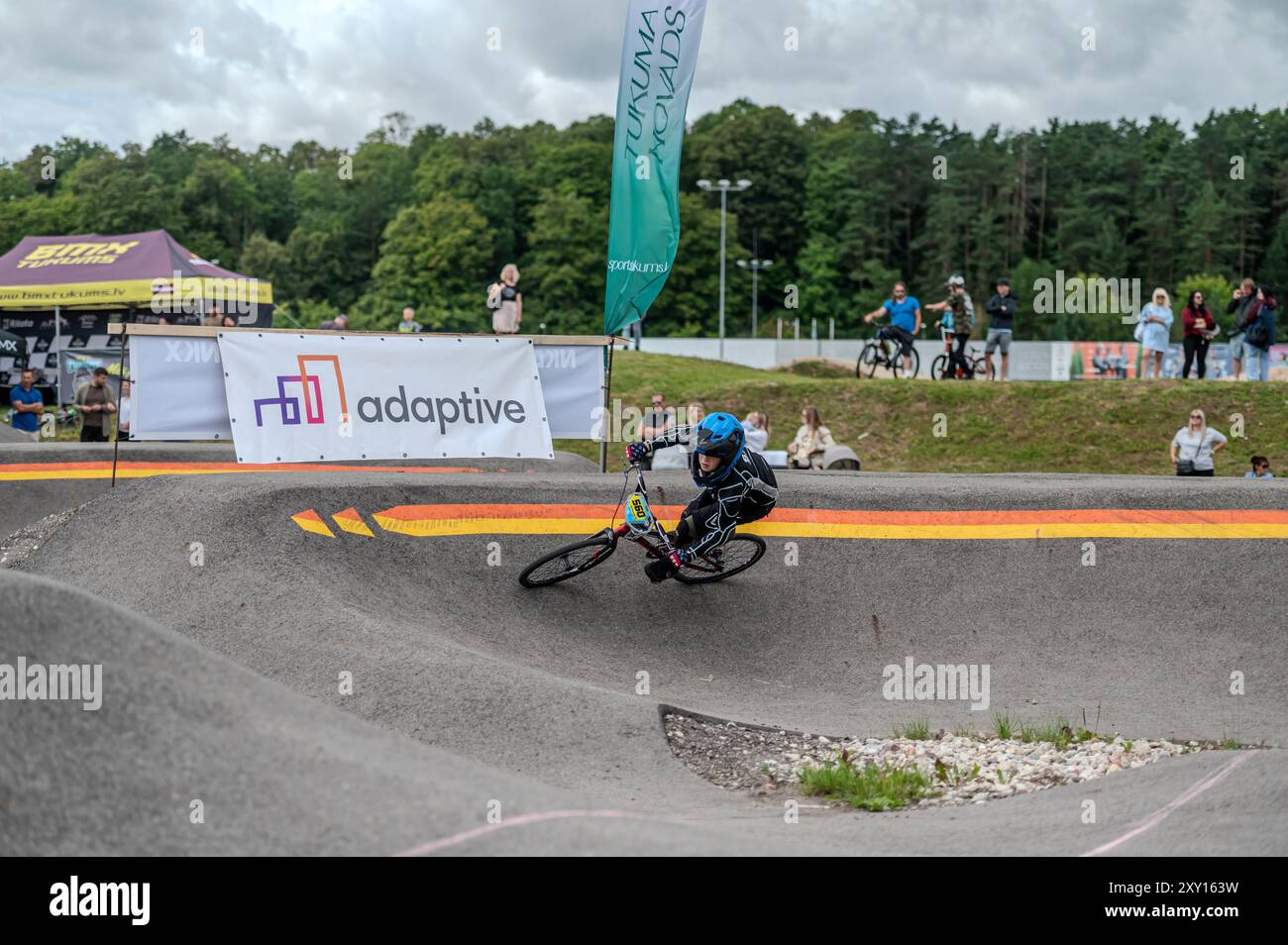 Tukums, Lettonie - 10 août 2024 : pilote de BMX naviguant sur une piste de pompage lors d'une compétition dans un parc naturel Banque D'Images