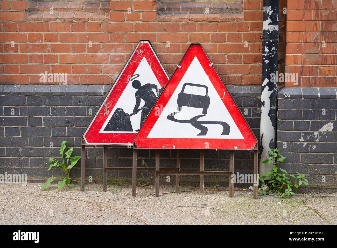 Travaux routiers et signalisation routière glissante contre un mur de briques Banque D'Images
