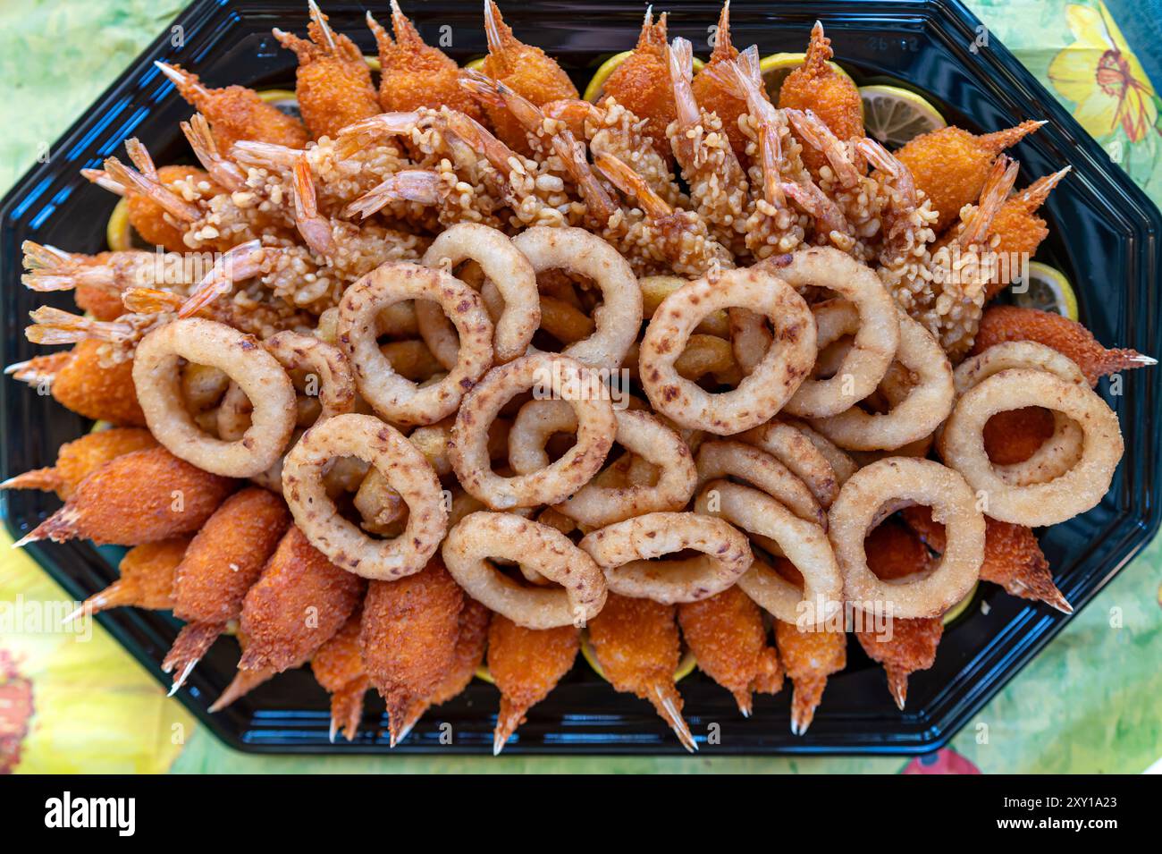 Un assortiment éclatant de crevettes frites et de rondelles d'oignon présentées magnifiquement sur un plateau noir. Banque D'Images