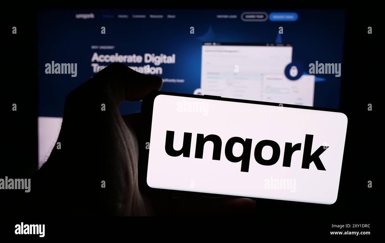 Personne tenant le téléphone mobile avec le logo de la société américaine de plate-forme d'application d'entreprise Unqork Inc en face de la page Web. Concentrez-vous sur l'affichage du téléphone. Banque D'Images