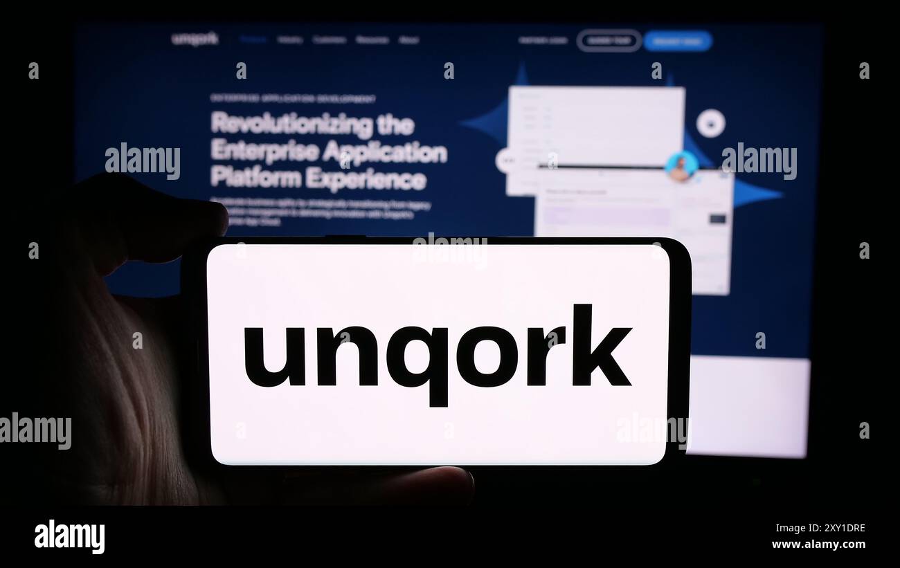 Personne tenant le téléphone portable avec le logo de la société américaine de plate-forme d'application d'entreprise Unqork Inc en face de la page Web. Concentrez-vous sur l'affichage du téléphone. Banque D'Images