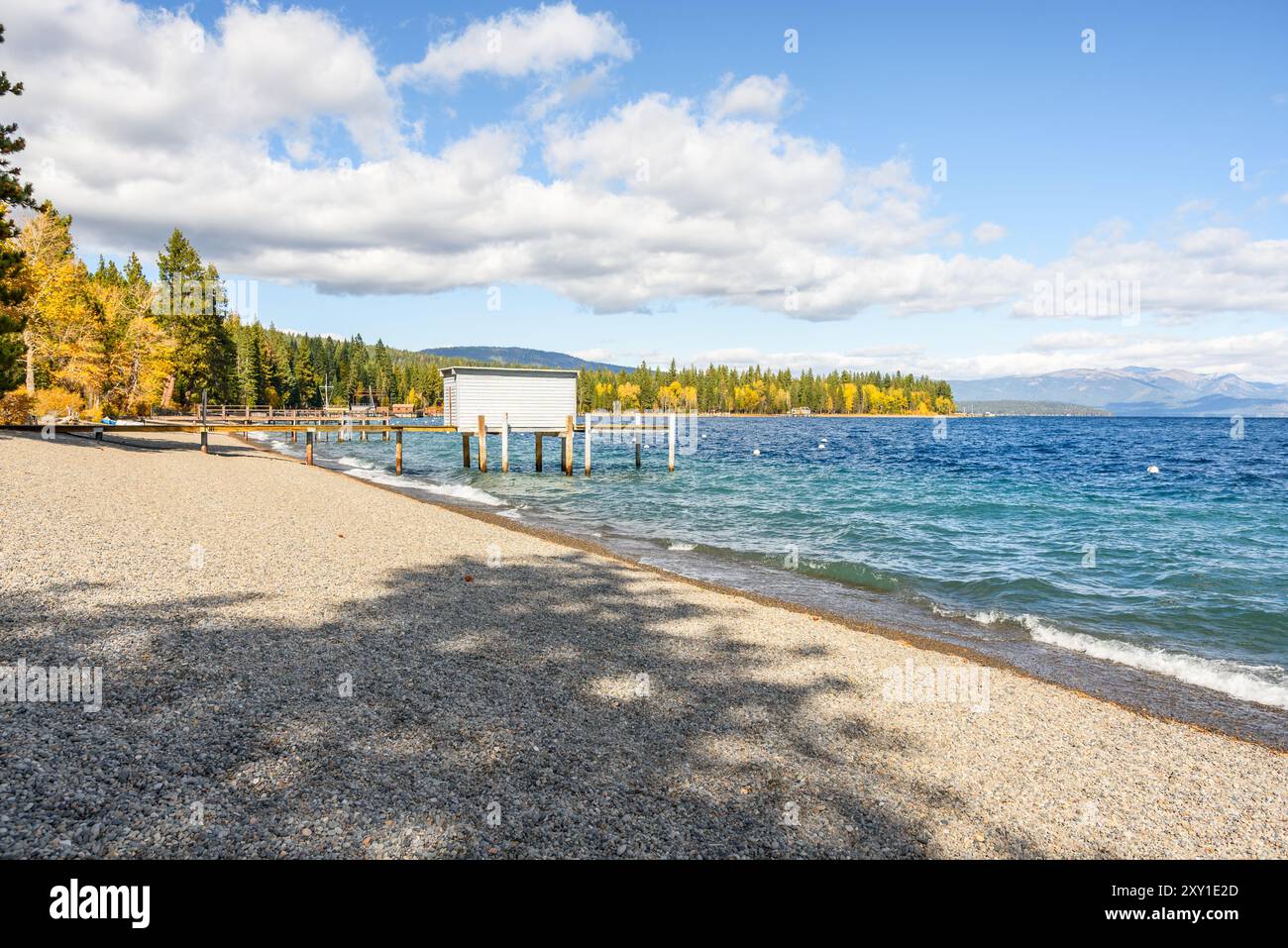 Plage de galets vide avec des jetées en bois bordées de forêt sur un lac de montagne par un jour ensoleillé d'automne. Un hangar à bateaux en bois sur une jetée. Lake tahoe, CA, U. Banque D'Images