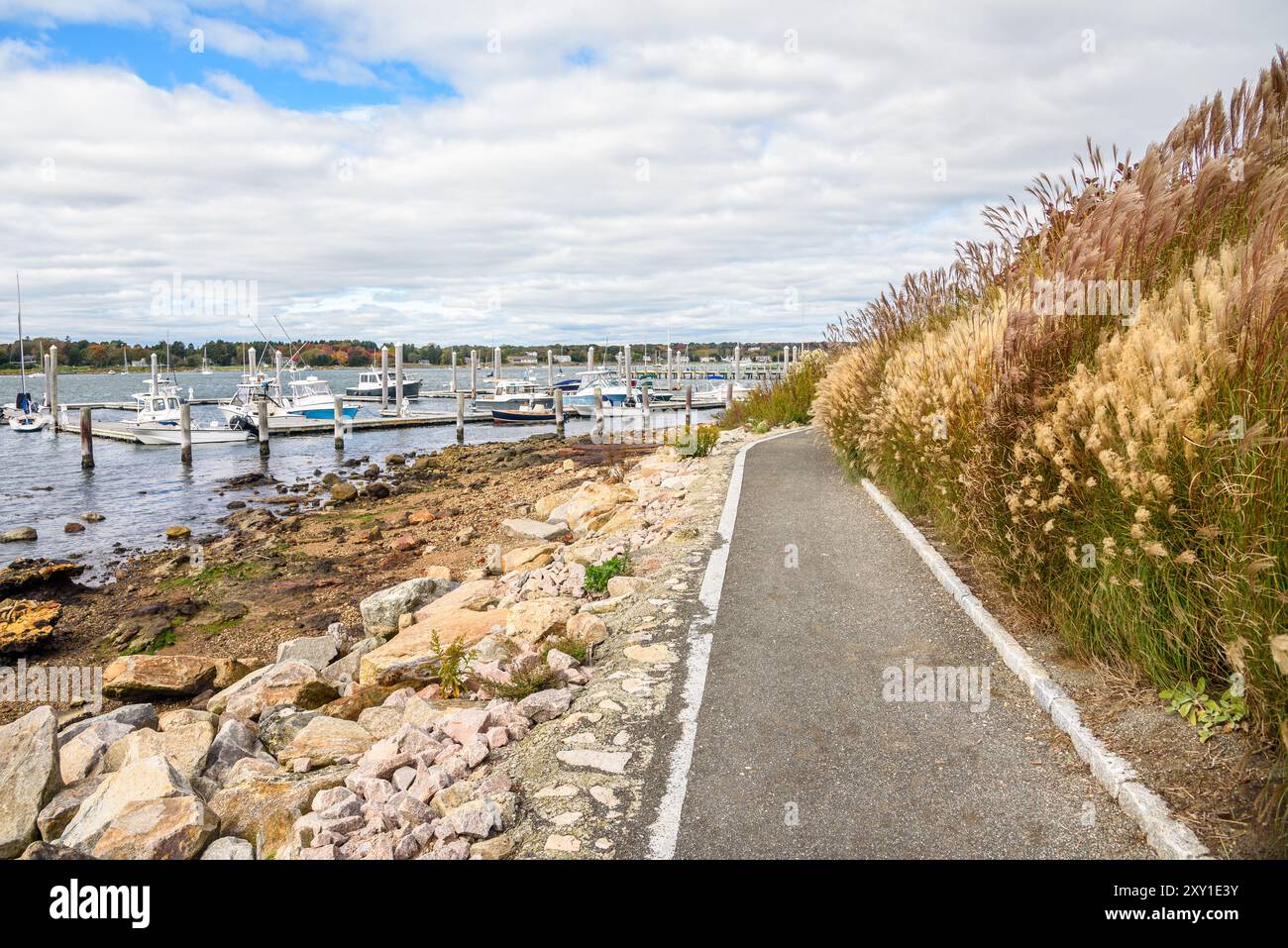 Sentier piétonnier déserté au bord du port par un jour nuageux d'automne. Les bateaux amarrés aux jetées sont en arrière-plan Banque D'Images
