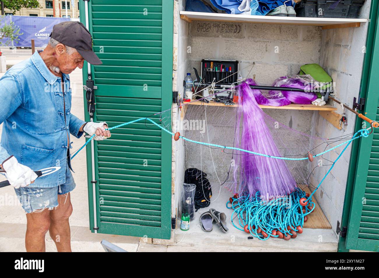 Cannes France,Côte d'Azur,Vieux-Port de Cannes marina,homme senior pêcheur,réparation filet de pêche,larynx tube de gorge respiration feed Banque D'Images