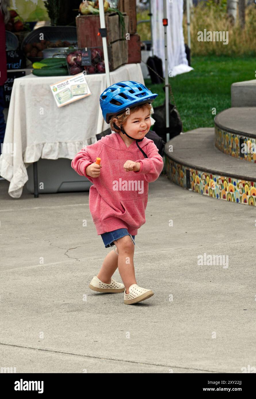 Une jeune fille de quatre ans dansant au son de la musique live dans un marché fermier dans le centre de l'Oregon. Banque D'Images