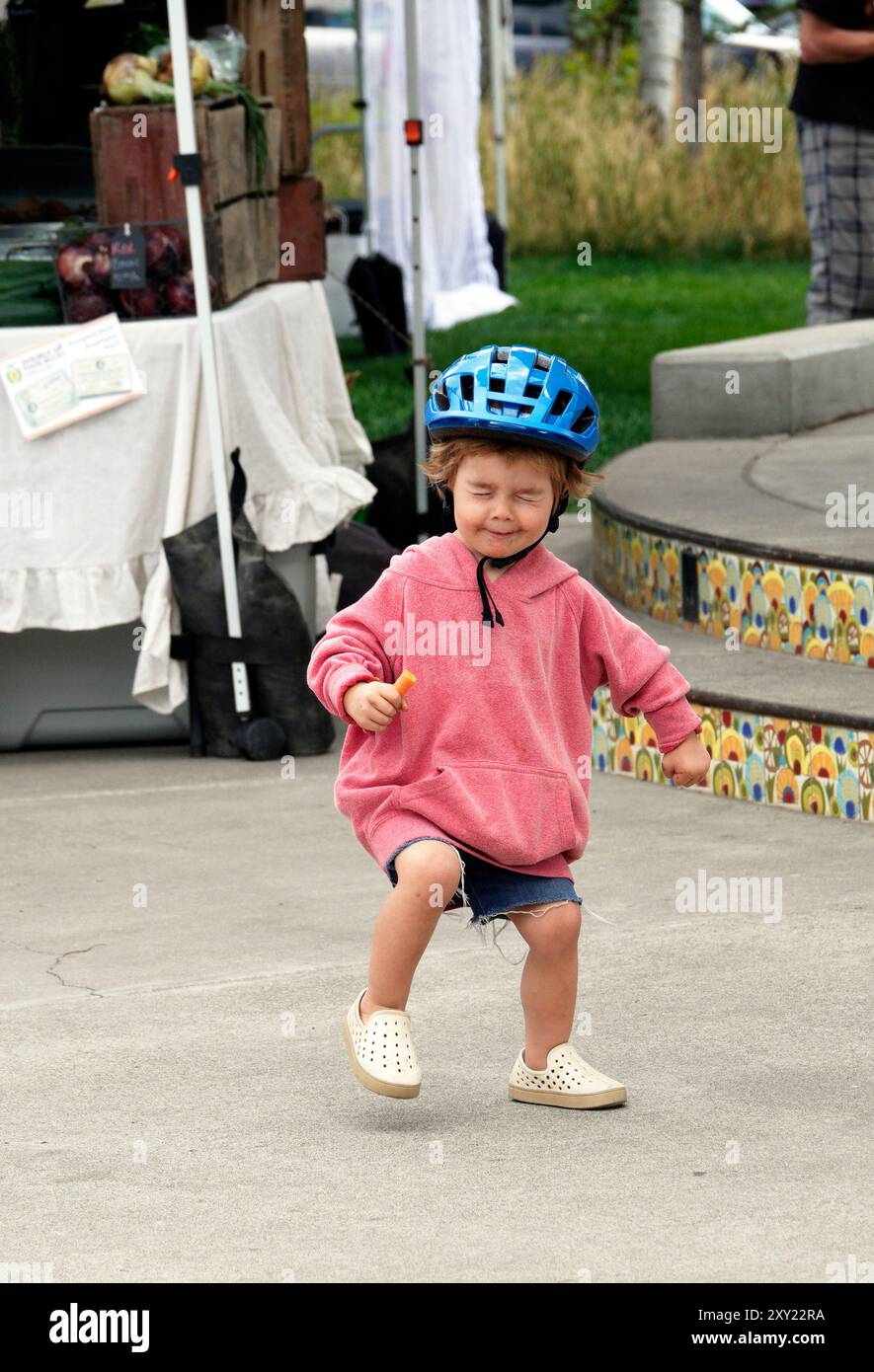 Une jeune fille de quatre ans dansant au son de la musique live dans un marché fermier dans le centre de l'Oregon. Banque D'Images