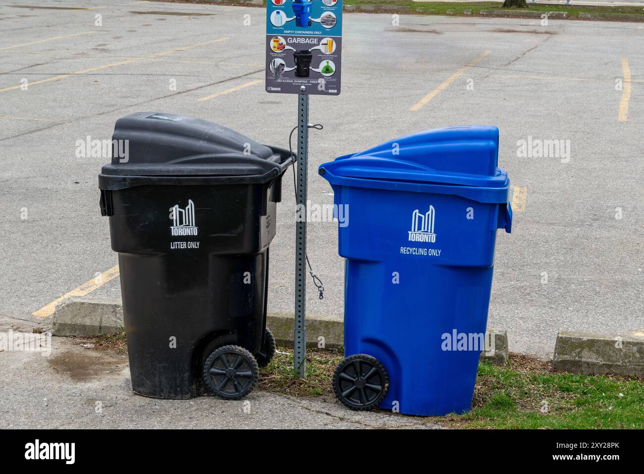 Toronto, Canada, 08APR2024 - poubelles noires et bacs de recyclage bleus avec plaque d'instructions sur un parking public Banque D'Images