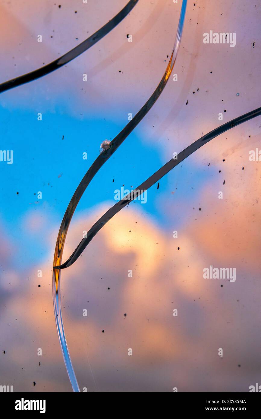 Un gros plan de verre brisé avec un ciel vibrant et des nuages en arrière-plan. Banque D'Images