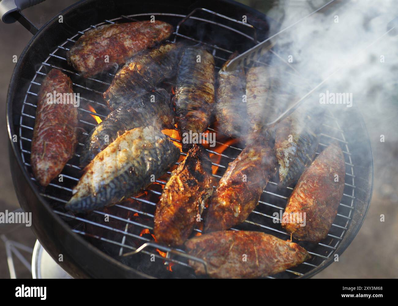 Filets de poissons sur le grill avec des flammes en orientation horizontale Banque D'Images