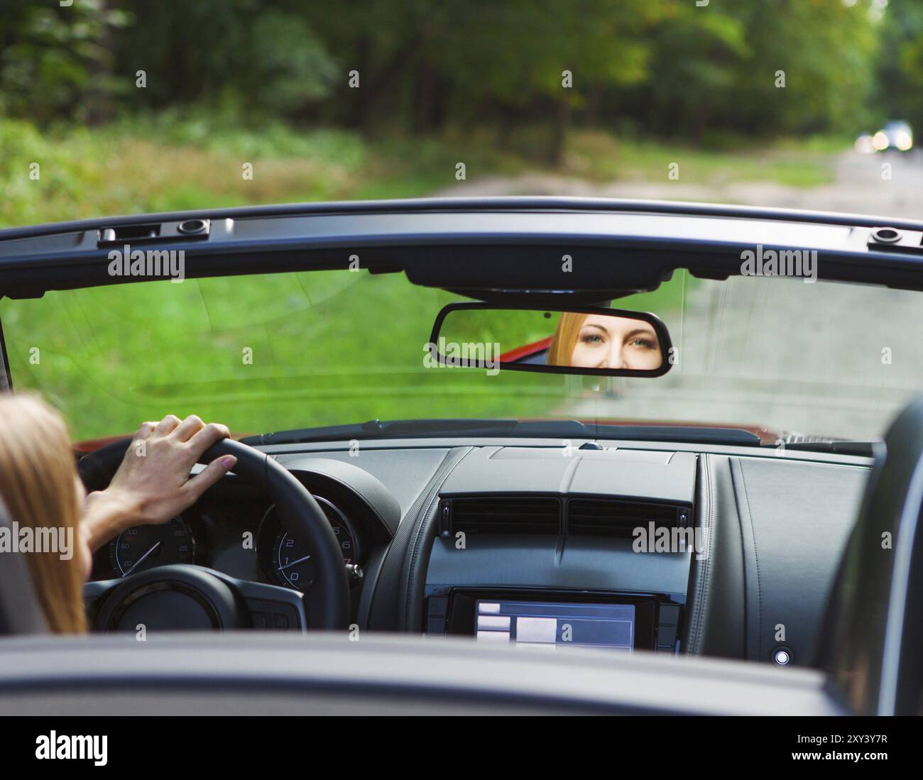 Belle blonde jeune femme au volant d'une voiture de sport sur la route Banque D'Images