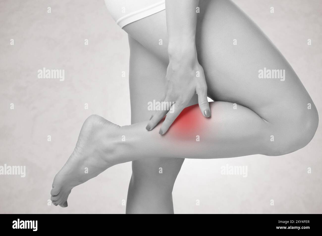 Femelle avec douleur dans sa jambe, isolé en gris Banque D'Images