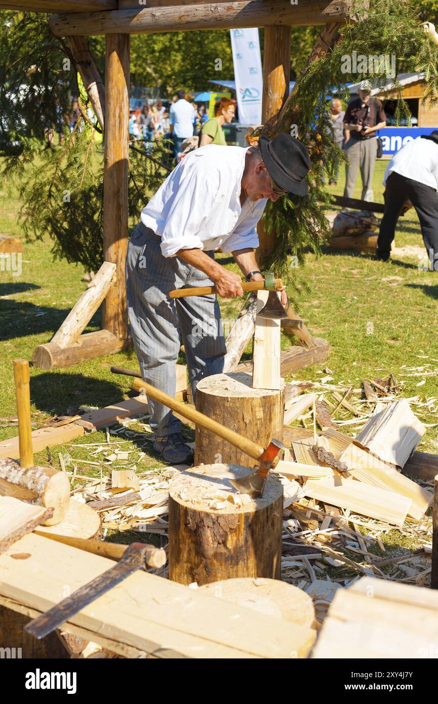 Annecy, France, 6 juillet 2012 : un homme âgé utilise des méthodes et des outils traditionnels de la région des Alpes françaises de haute-Savoie pour couper des pièces en bois pour la cabane c. Banque D'Images