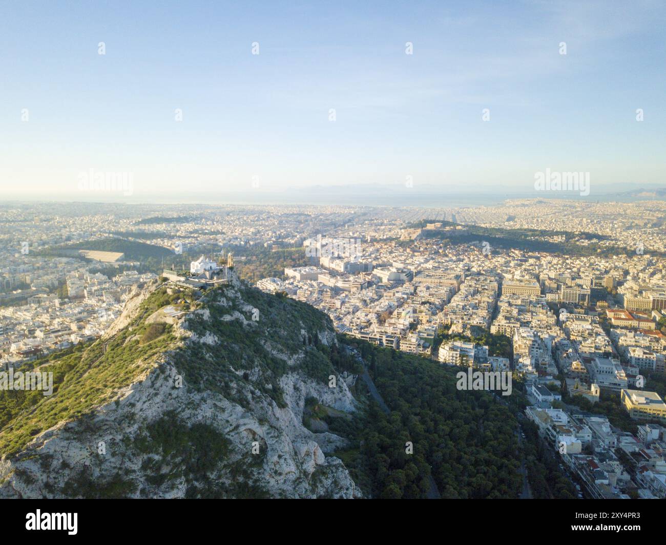 Vue aérienne par drone du mont Lycabette surplombant le paysage urbain jusqu'à la mer Méditerranée à Athènes, Grèce, Europe Banque D'Images
