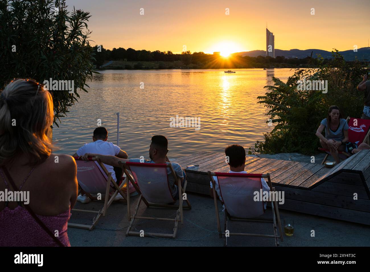 Jeunes assis sur la rive du Nouveau Danube à Copa Beach au coucher du soleil, Vienne, Autriche Banque D'Images