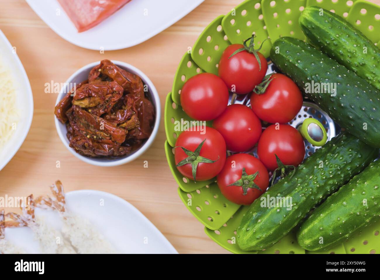 Nature morte de la nourriture crue dans des assiettes blanches sur une table en bois. Saumon congelé sur une assiette à côté de concombres et tomates fromage râpé et crevettes crues en bre Banque D'Images