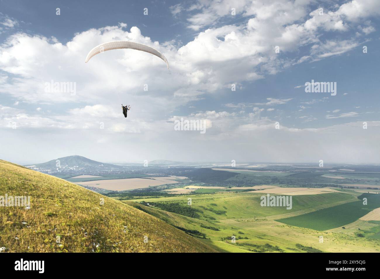 Parapente d'orange blanche avec parapente dans un cocon sur fond de champs du ciel et de nuages. Parapente Sports Banque D'Images