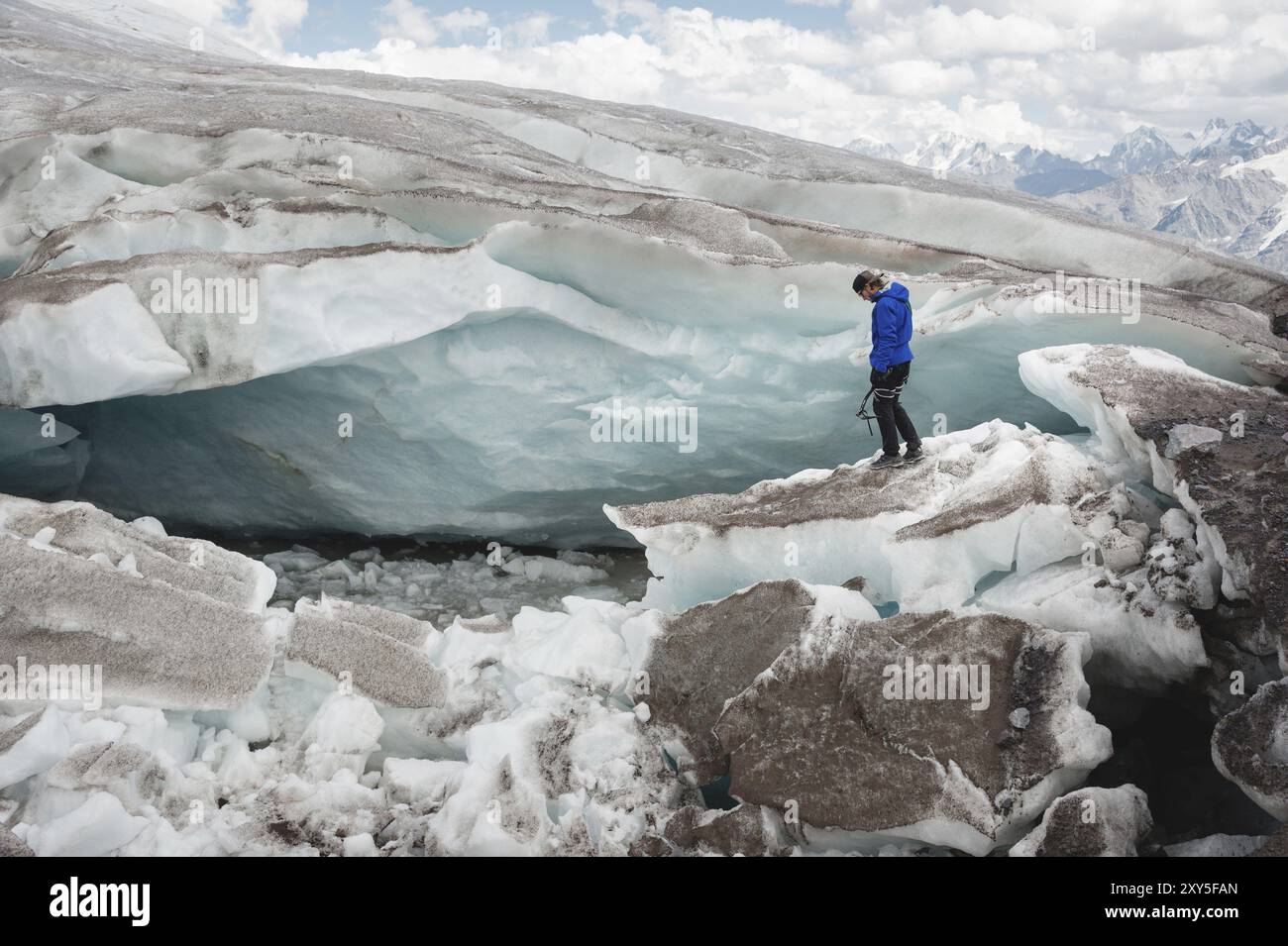 Le voyageur dans une casquette et des lunettes de soleil est assis dans les montagnes enneigées sur le glacier. Voyageur dans un environnement naturel Banque D'Images