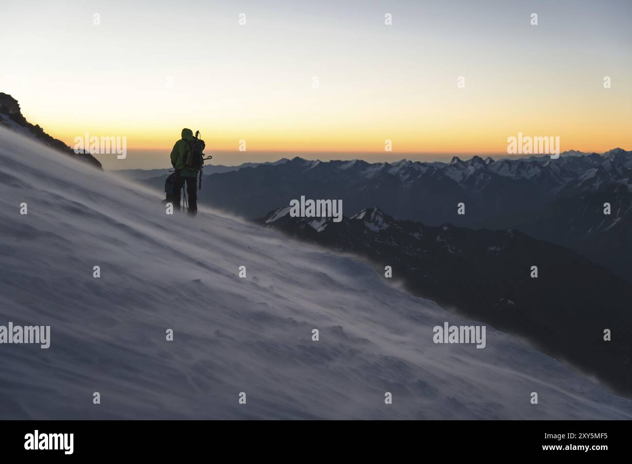 L'alpiniste professionnellement équipé à l'aube du soleil marche sur la pente au petit matin et la neige dérive sur la neige au-dessus de la neige. T Banque D'Images