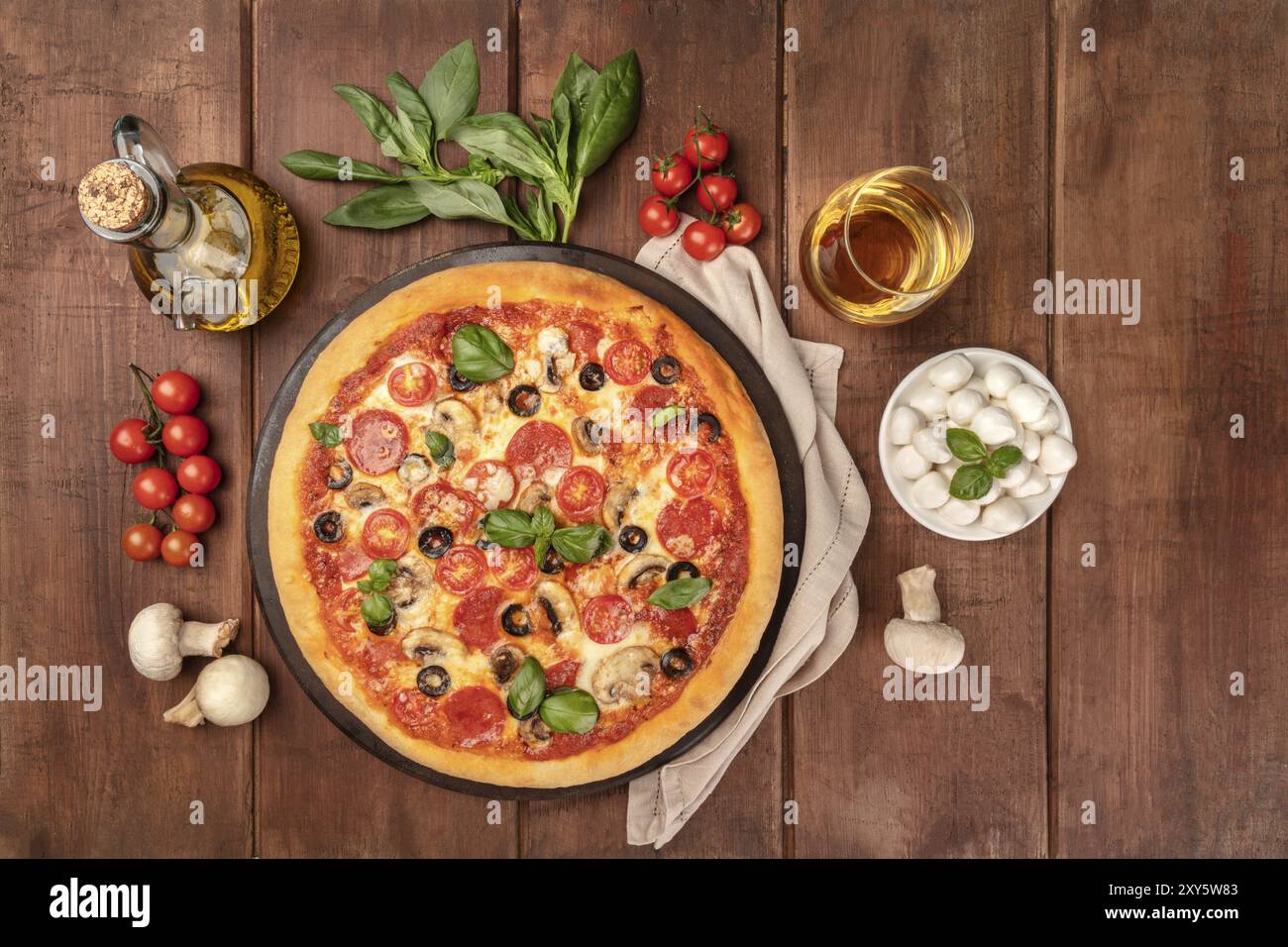 Photo prise à la verticale de la pizza au pepperoni, avec verre de vin blanc, huile d'olive, les feuilles de basilic, champignons, tomates cerises et mozzarellini fromage, tourné à partir de la société abo Banque D'Images
