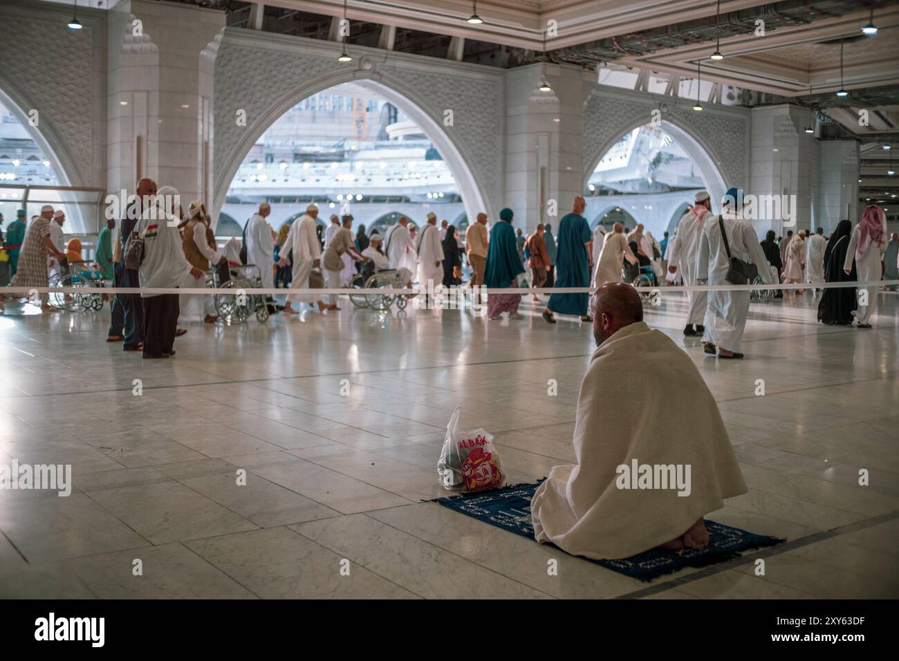 Un pèlerin musulman non identifié regarde d'autres pèlerins effectuer des tawaf (circumambulation) de la Kaaba au deuxième étage de la mosquée sainte Masjid Haram à la Mecque. Banque D'Images