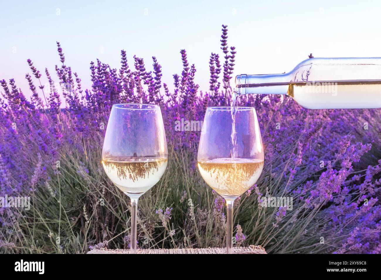 Vin de lavande. Vin blanc versé d'une bouteille dans des verres contre un champ lavande background Banque D'Images Vin de lavande. Vin blanc versé d'une bouteille dans des verres contre un champ lavande background Banque D'Images