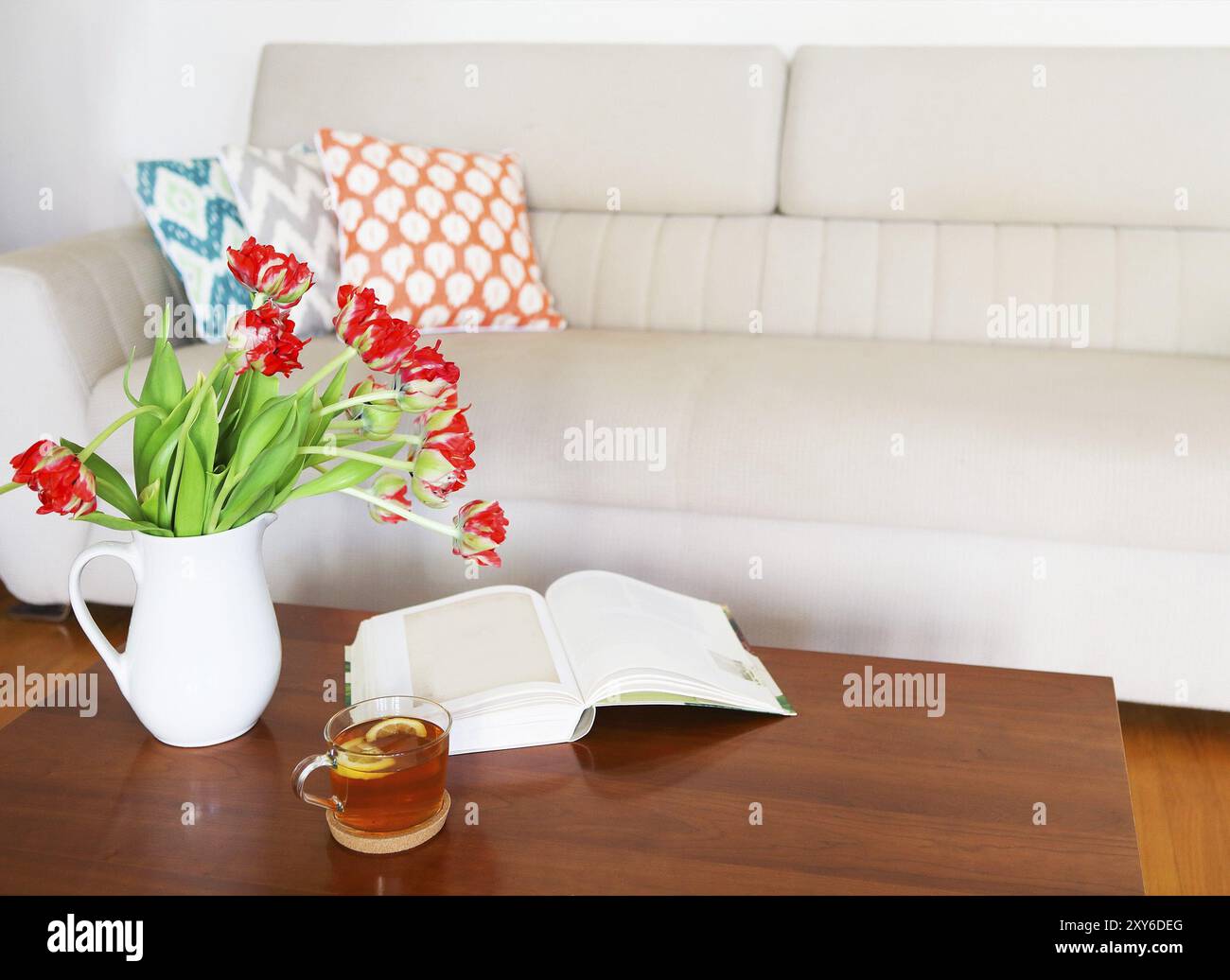 Beau bouquet de tulipes orange avec un plateau et le livre sur la table en bois dans le salon Banque D'Images