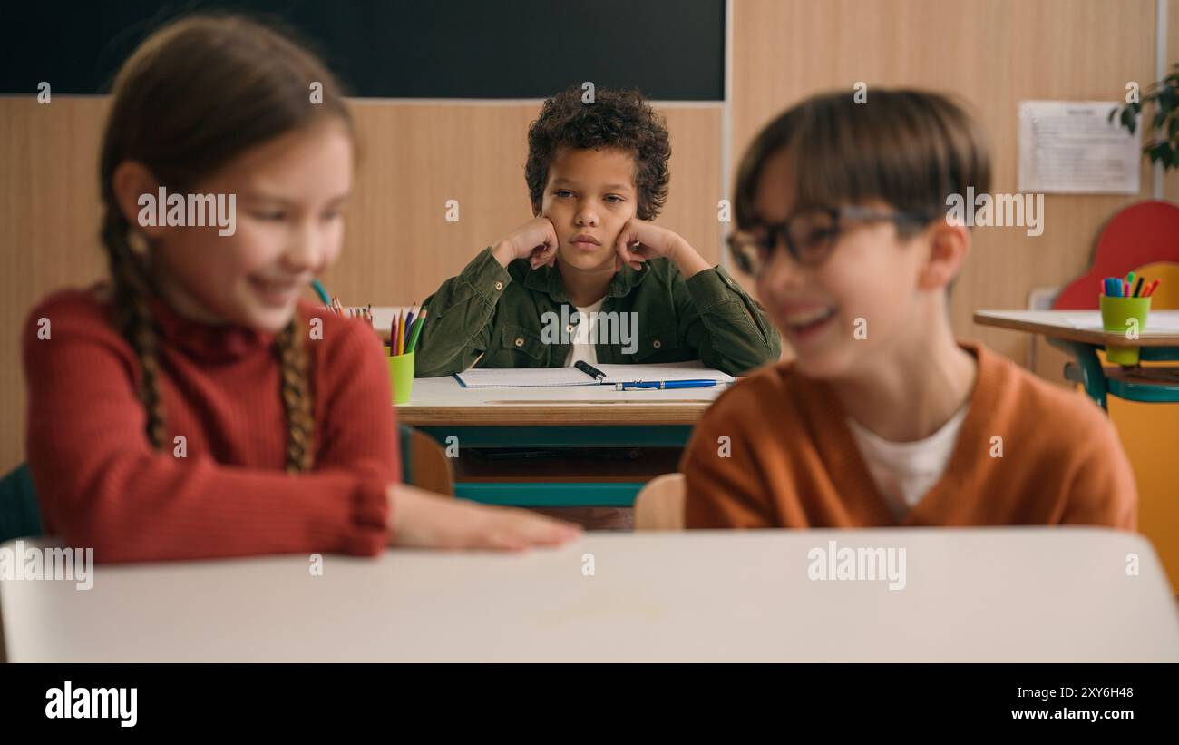 Deux enfants caucasiens leçon d'école fille garçon camarades de classe rire diabolique rire moquer intimidateur afro-américain enfant écolier triste bouleversé Banque D'Images