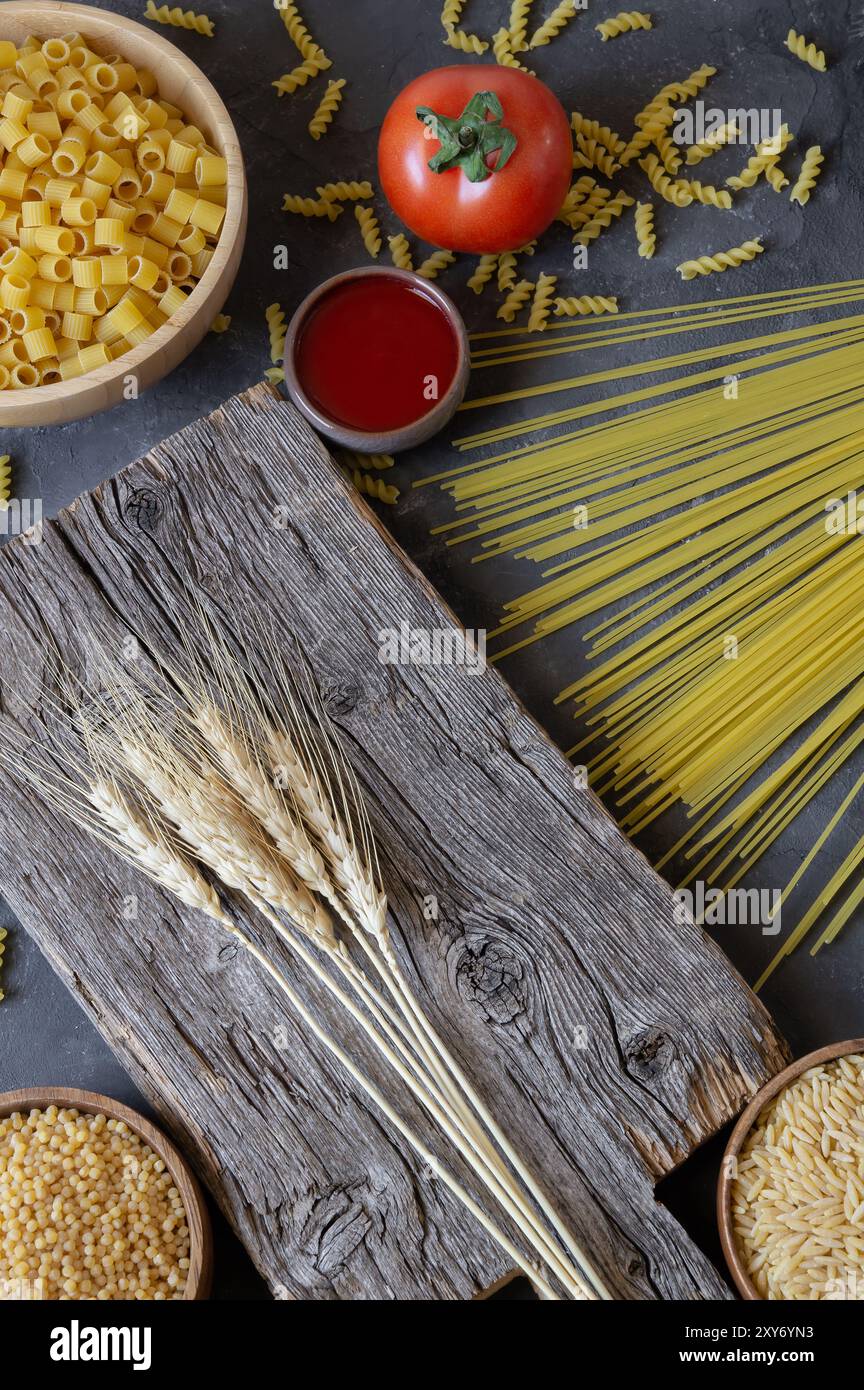 Diverses pâtes crues avec planche à découper sur fond de pierre, concept de nourriture non cuite Banque D'Images