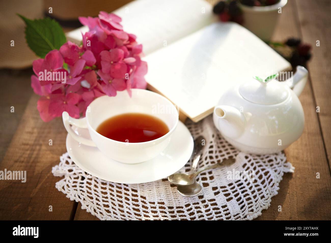 Du dessus de la tasse de thé rouge et de thé blanc en céramique sur table en bois avec des fleurs roses et livre ouvert Banque D'Images