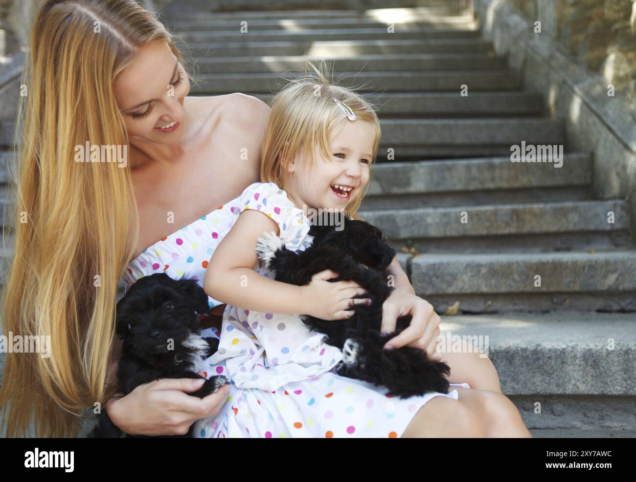 Jolie petite fille et sa mère hugging dog chiots. L'amitié et de concept de soins Banque D'Images