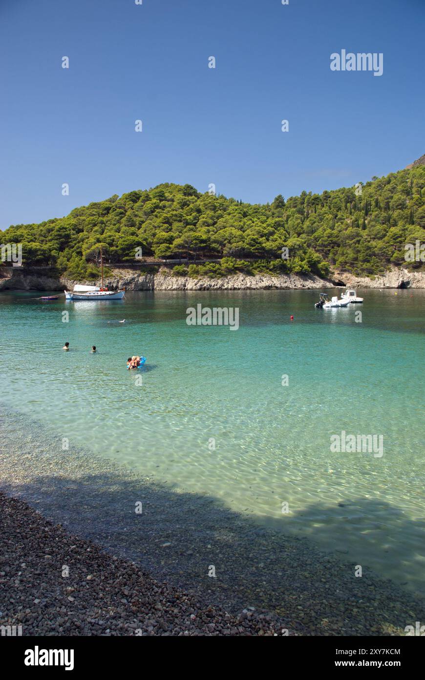 Veduta di una baia con acqua limpida tra le rocce e alcune barche Banque D'Images