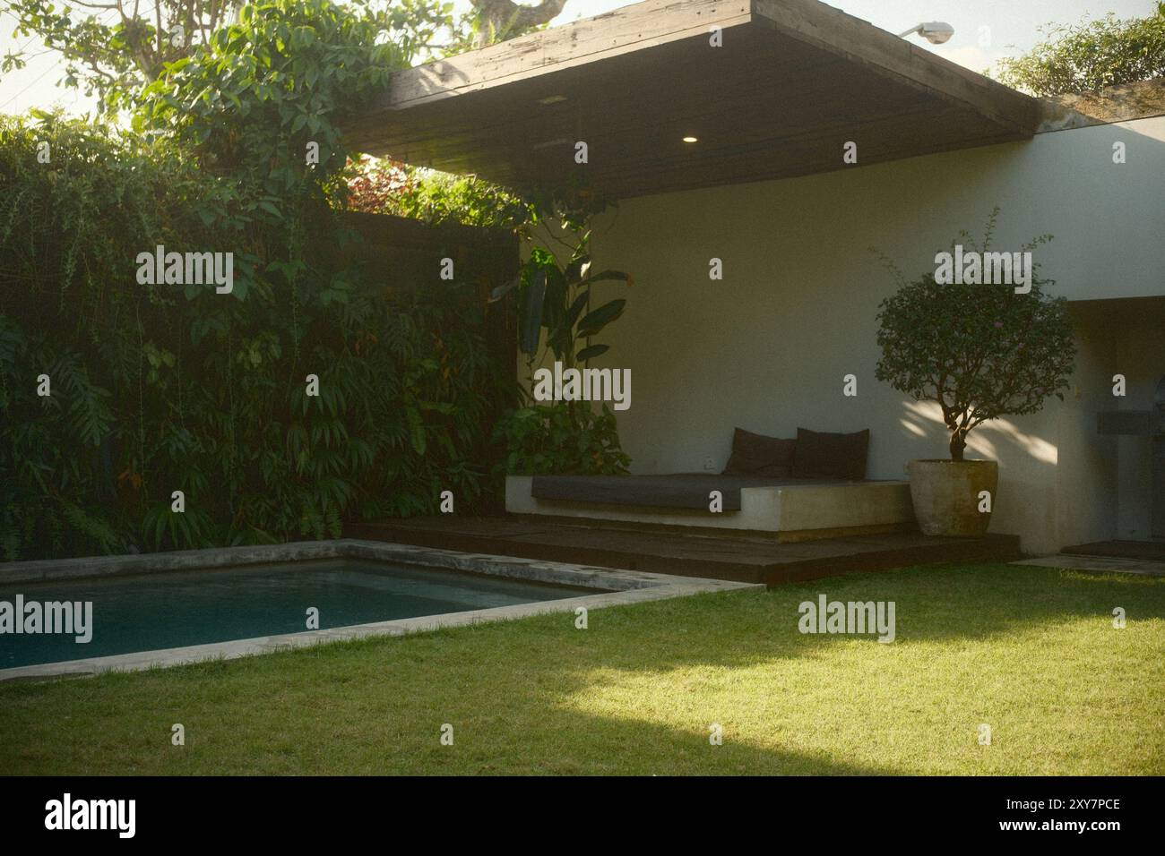 Salon extérieur près de la piscine avec lits, jardin vertical, zone herbeuse et piscine privée dans une villa de luxe Banque D'Images