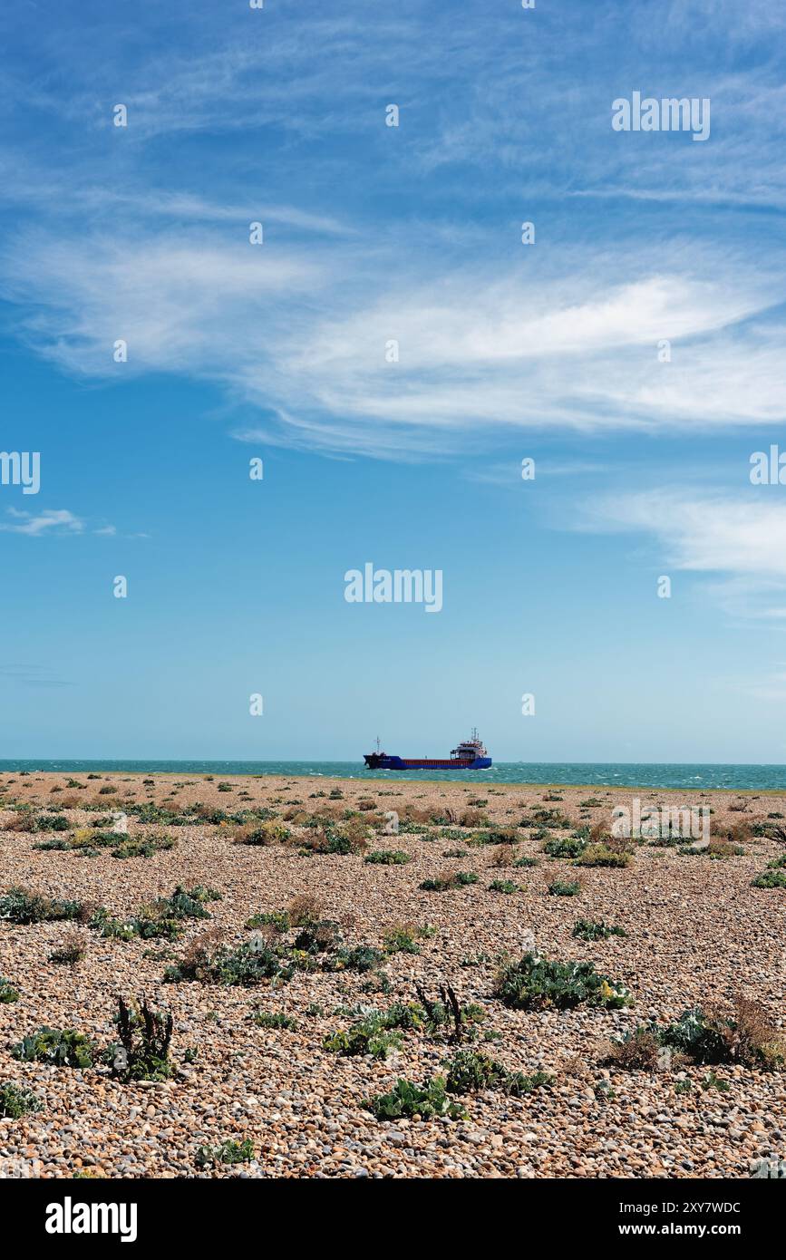Un petit bateau cargo sur le point d'entrer dans le port de Shoreham par une journée d'été ensoleillée avec plage de galets au premier plan West Sussex England UK Banque D'Images