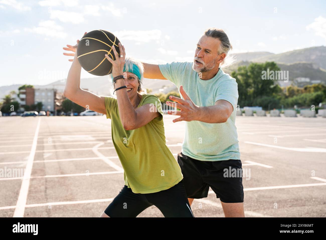 Beau couple senior heureux jouant au basket-ball et s'amusant - couple marié mature dans l'amour se lier à l'extérieur et faire du sport ensemble, concepts ab Banque D'Images