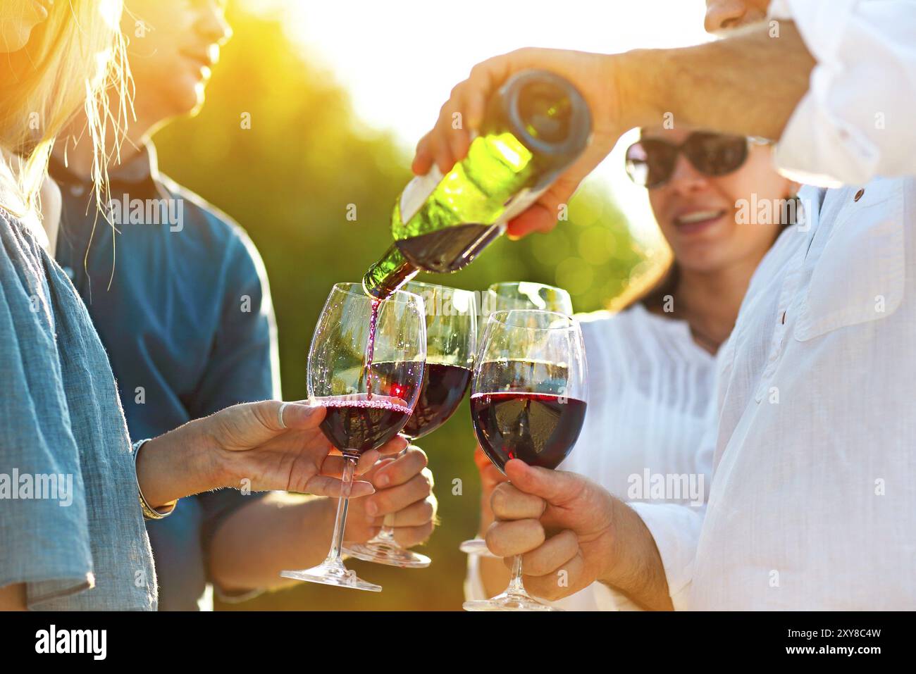 Les gens à l'extérieur du vin partie. Fête du vin. Man pouring red wine in à l'wineglasses Banque D'Images Les gens à l'extérieur du vin partie. Fête du vin. Man pouring red wine in à l'wineglasses Banque D'Images