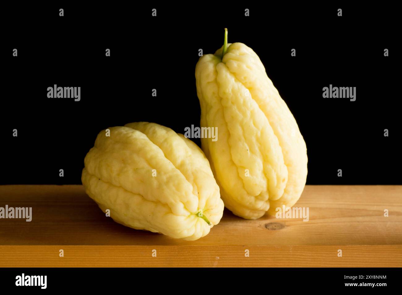 nature morte de deux chayote jaunes sur une étagère en bois sur un fond noir Banque D'Images