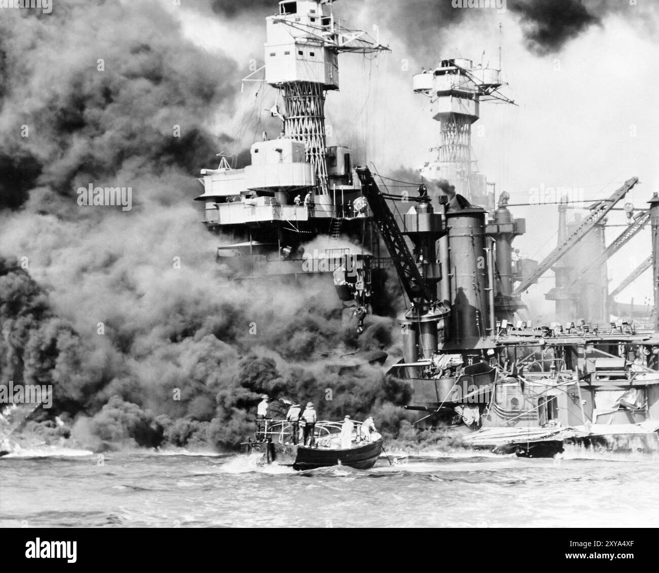 L'USS West Virginia brûle lors de l'attaque de Pearl Harbor à Hawaï le 7 décembre 1941, tandis qu'un bateau de sauvetage tire un marin de l'eau. Banque D'Images