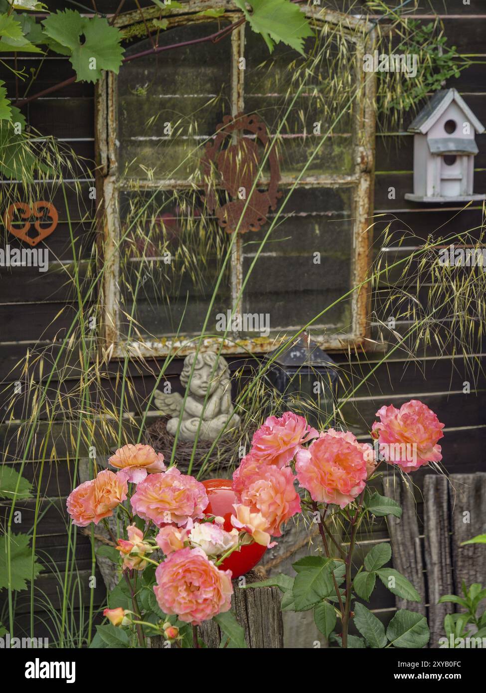 Fenêtre rustique dans un jardin, décorée de fleurs et d'une petite statue, entourée de verdure naturelle, borken, muensterland, allemagne Banque D'Images