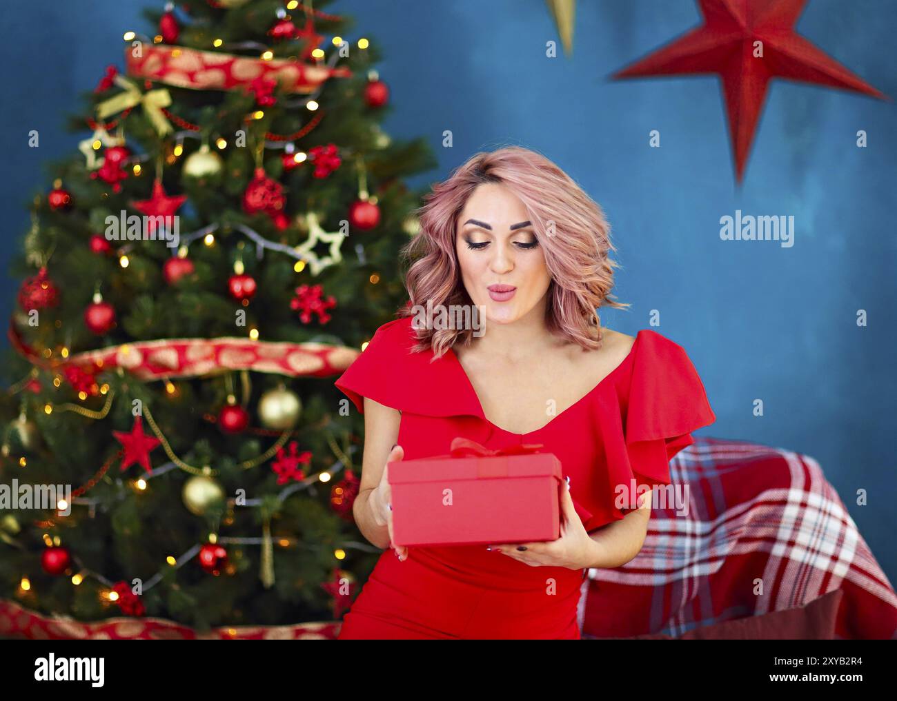 Smiling woman with gift box au salon sur fond d'arbre de Noël. Les vacances et les personnes concept. Temps de Noël Banque D'Images
