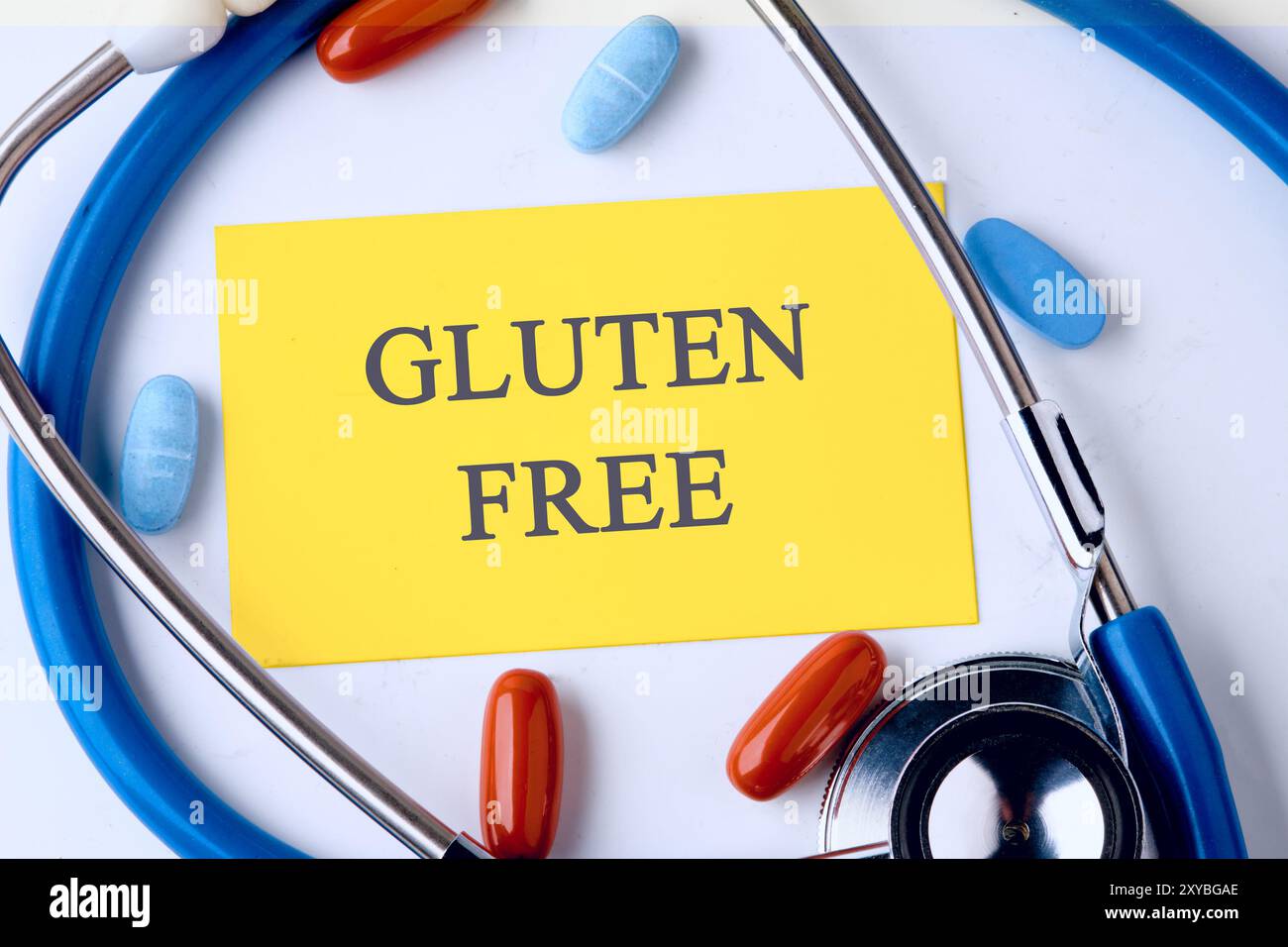 Mots SANS GLUTEN écrits sur une carte de visite jaune dans une composition avec un stéthoscope et des pilules Banque D'Images