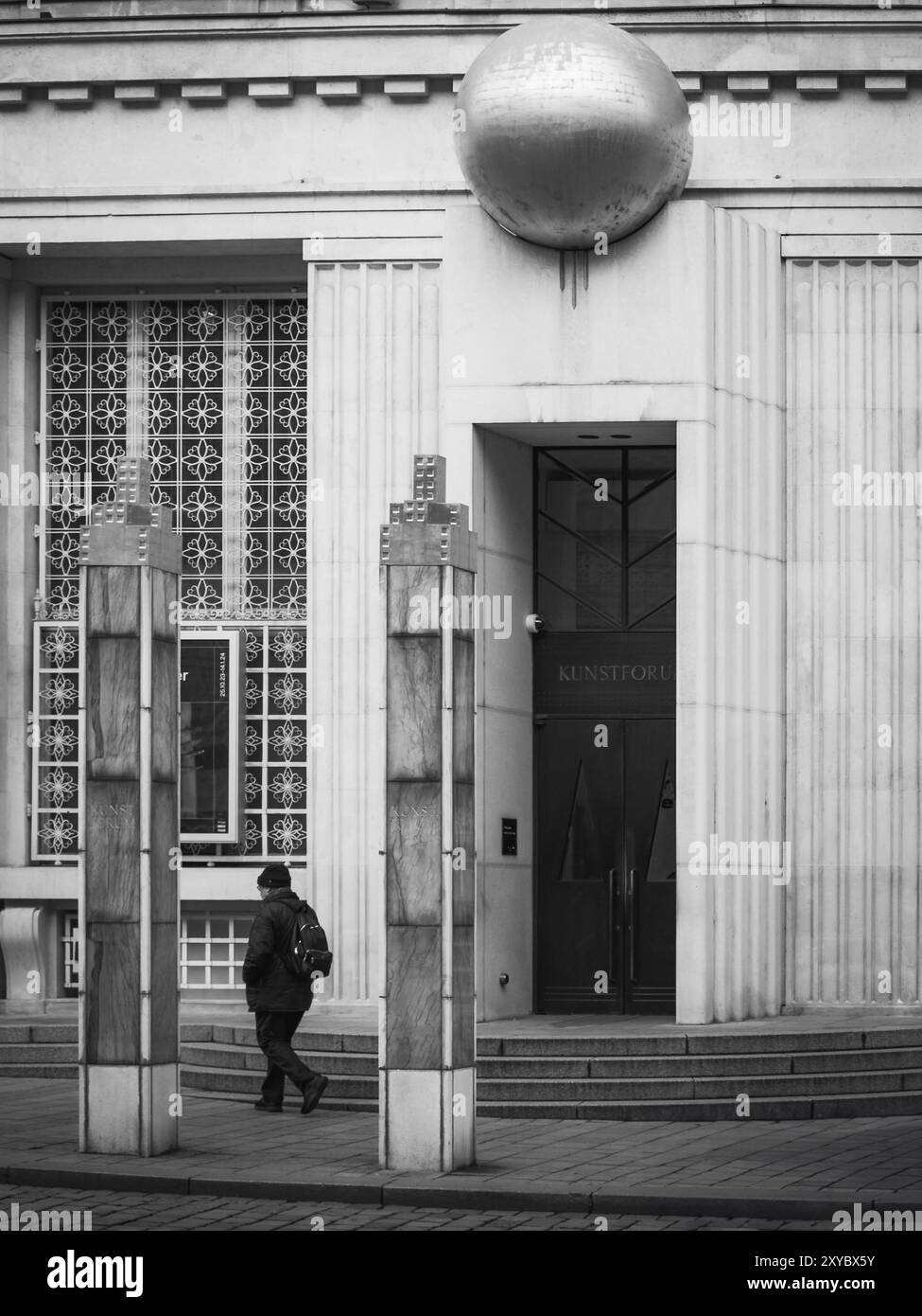 Photo en noir et blanc d'un homme encadré par deux colonnes devant le Kunstforum Vienna. Banque D'Images