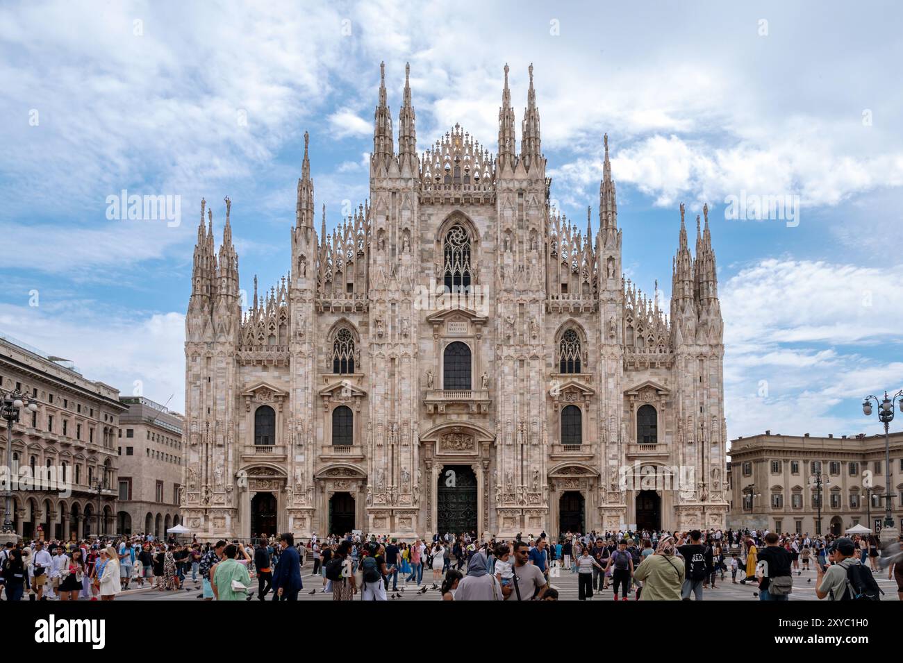 Touristes marchant sur la place du Duomo, avec l'imposante façade de la cathédrale Duomo di Milano en arrière-plan par une journée d'été ensoleillée Banque D'Images