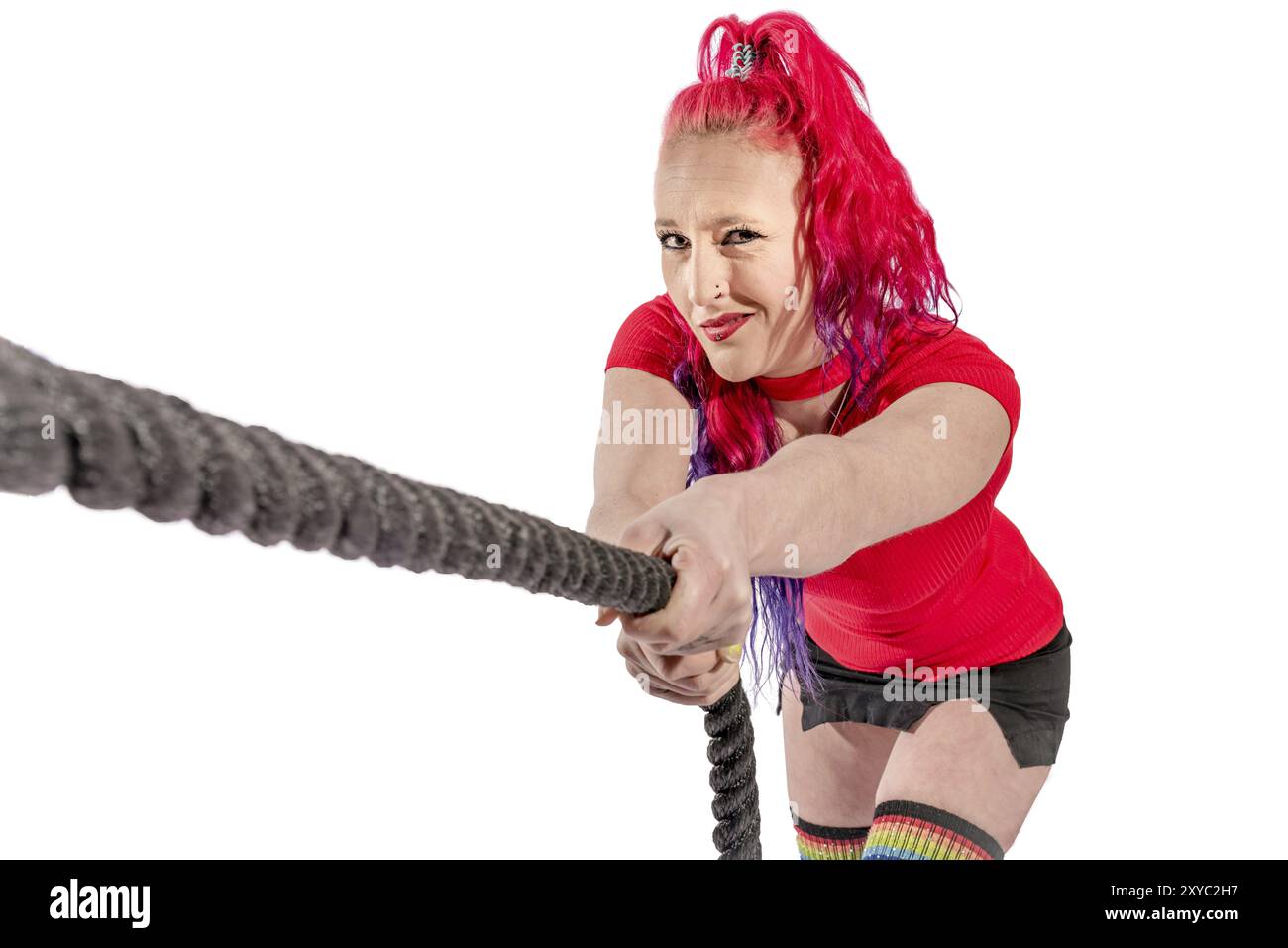 Femme avec cheveux rouges et jupe courte tire sur une corde Banque D'Images