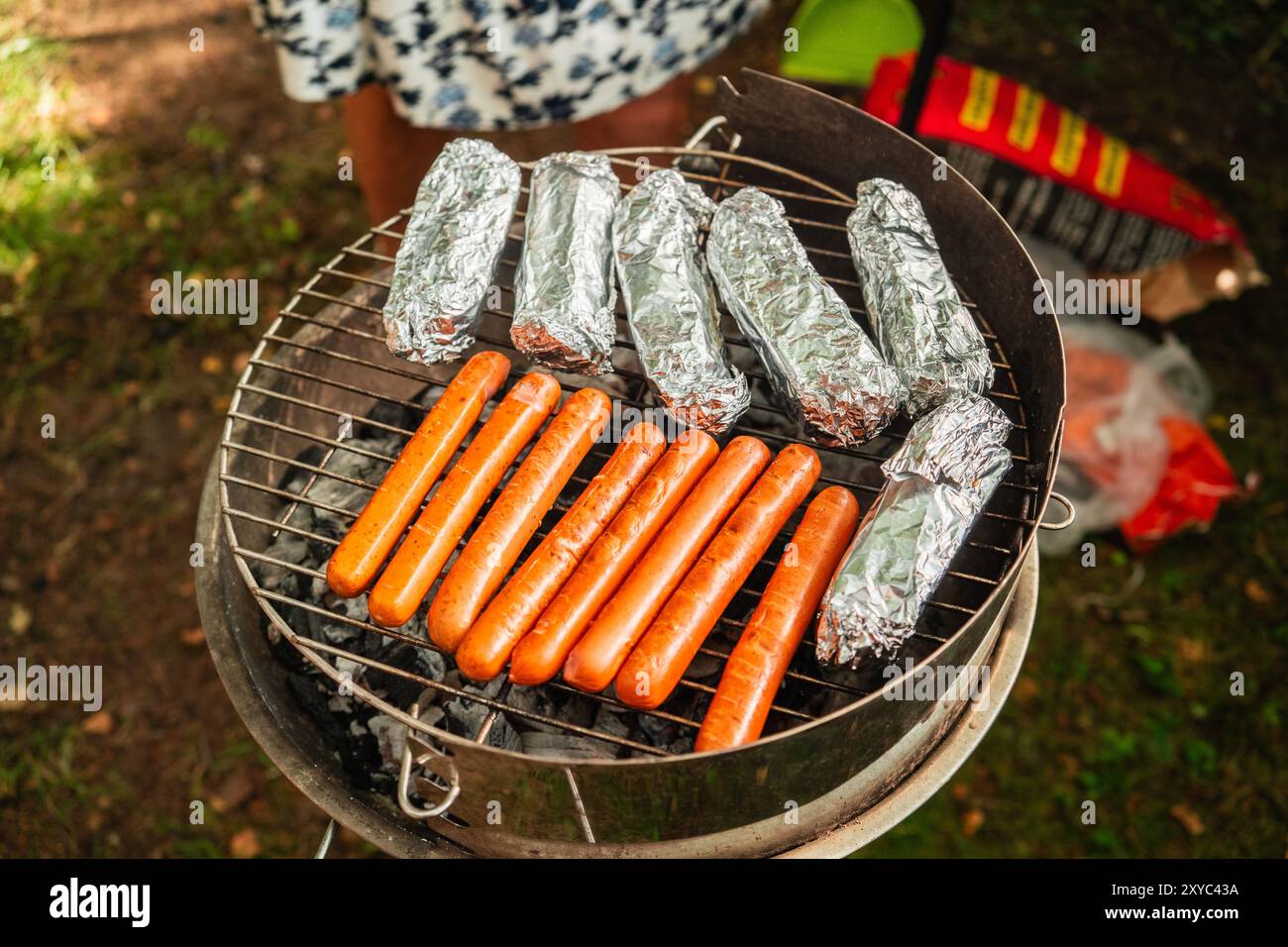 Saucisses végétariennes et fromage feta dans une feuille d'aluminium sur une grille chaude pendant la saison des grillades Banque D'Images