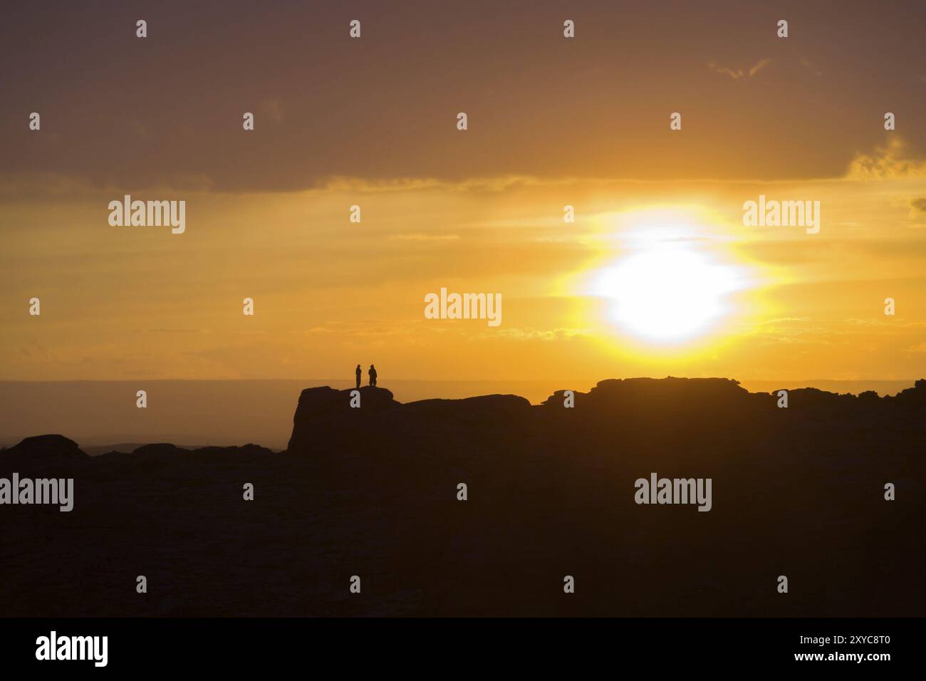 Deux personnes debout sur une crête de montagne lointaine silhouette par un grand soleil couchant juste au-dessus de l'horizon dans le désert de Gobi de Mongolie Banque D'Images