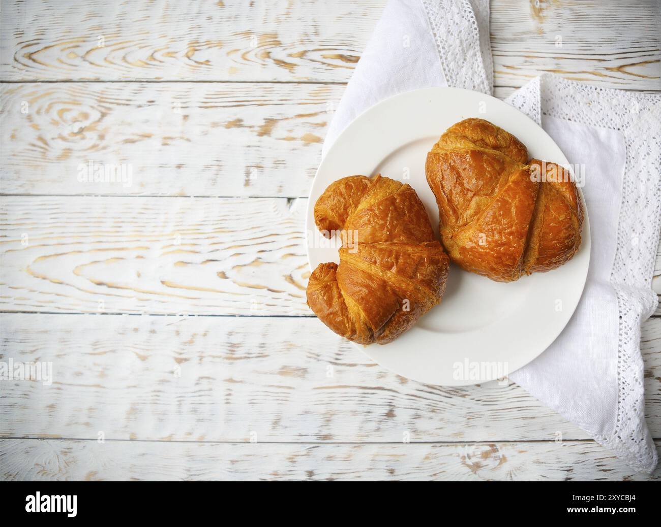 Deux délicieux croissants sur la plaque sur fond de bois. Vue d'en haut Banque D'Images