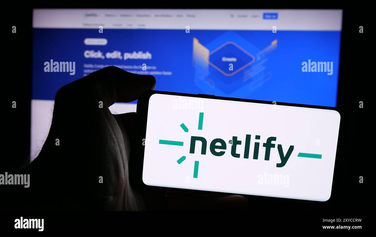 Personne tenant un smartphone avec le logo de la société américaine de plate-forme de développement Web Netlify Inc en face du site Web. Concentrez-vous sur l'affichage du téléphone. Banque D'Images